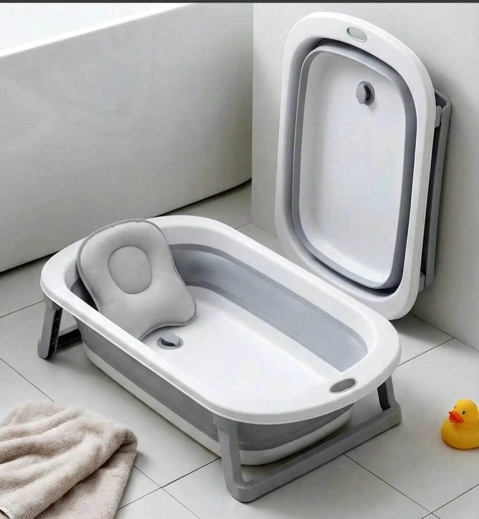 A white and gray foldable baby bathtub with a gray padded cushion insert, shown both expanded on the bathroom floor and folded against the wall.